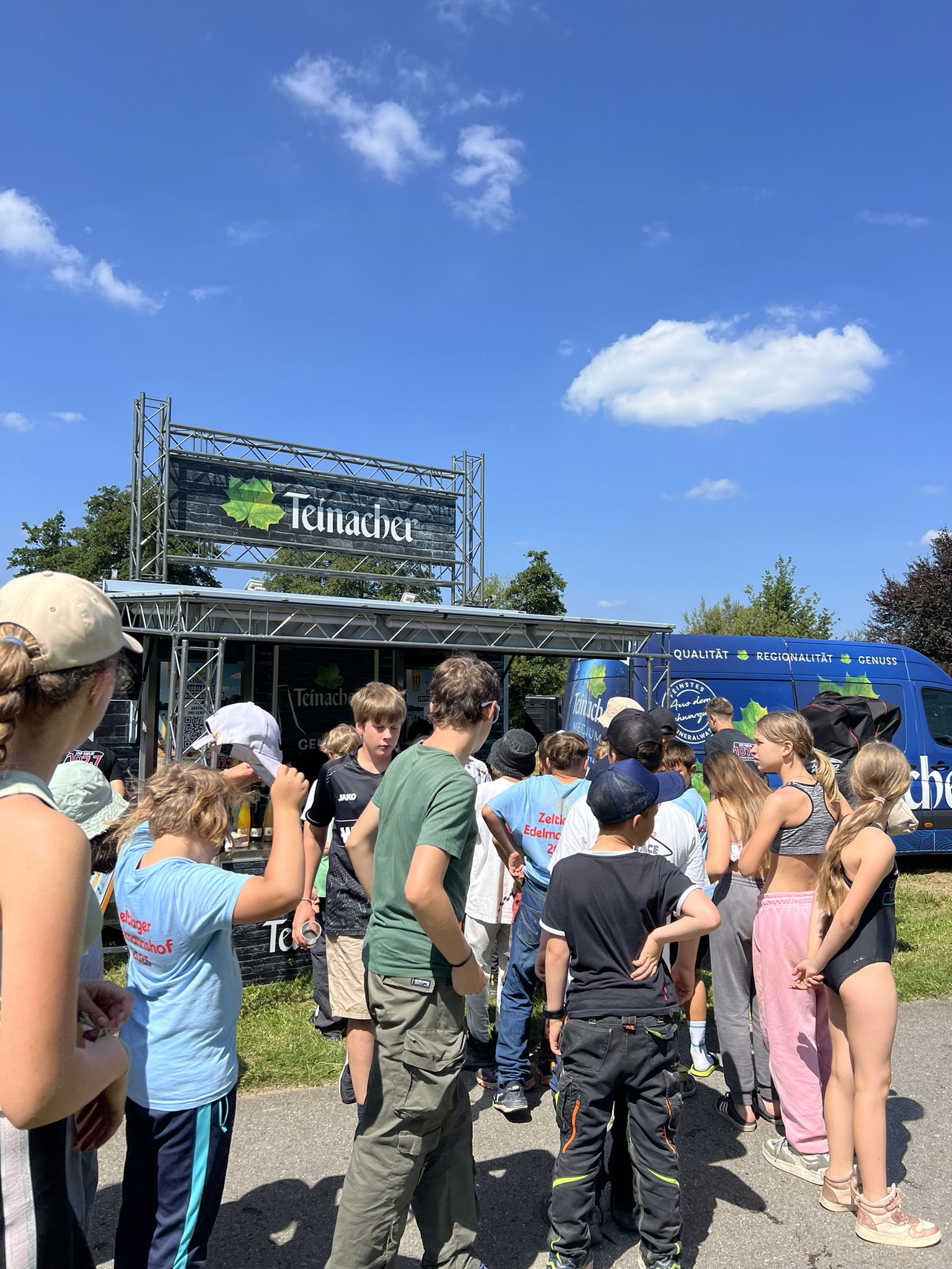 Eine Menschengruppe wartet vor dem Teinacher Stand